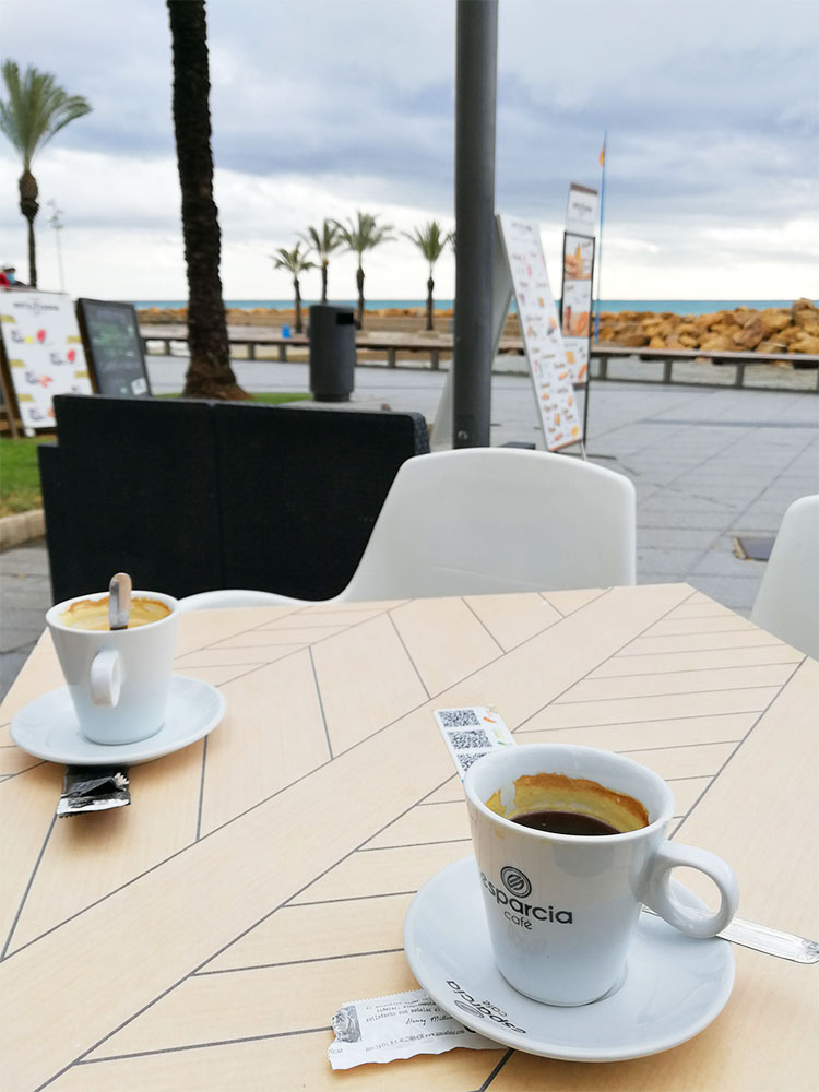 Två koppar kaffe på ett bord vid havet.