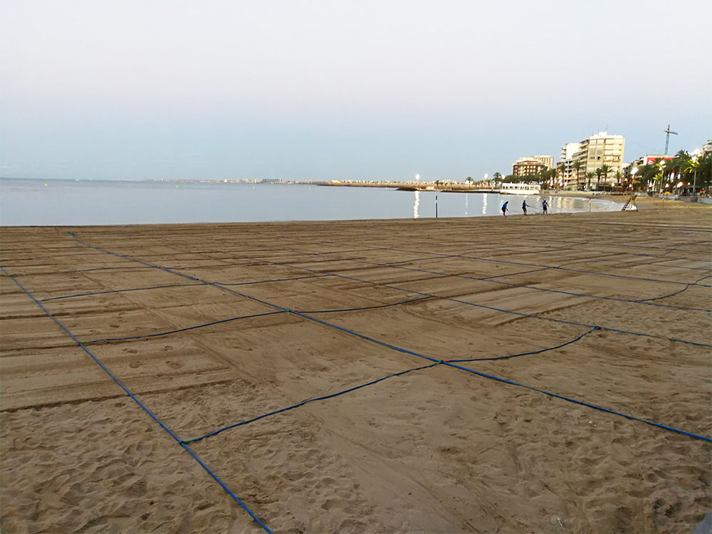 Strand med rep utlagda i fyrkanter.