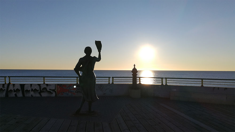 Staty av kvinna. Soluppgång över havet.