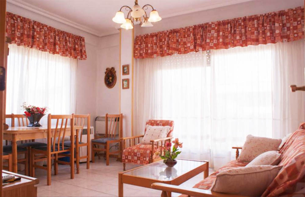 Vardagsrum med orange gardiner och orange soffgrupp.