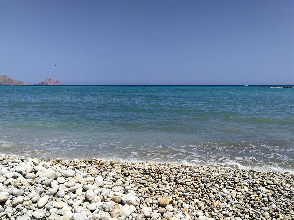 Turkost hav och stenig strand.