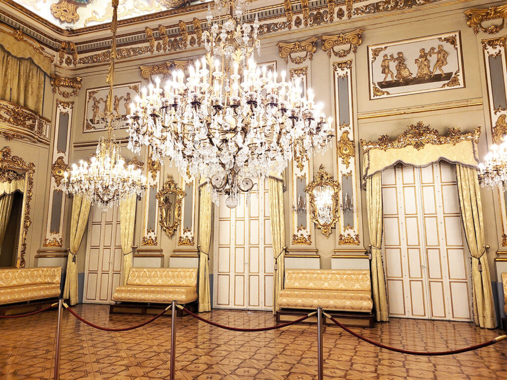 Rum med guldiga väggar och stora kristallkronor.