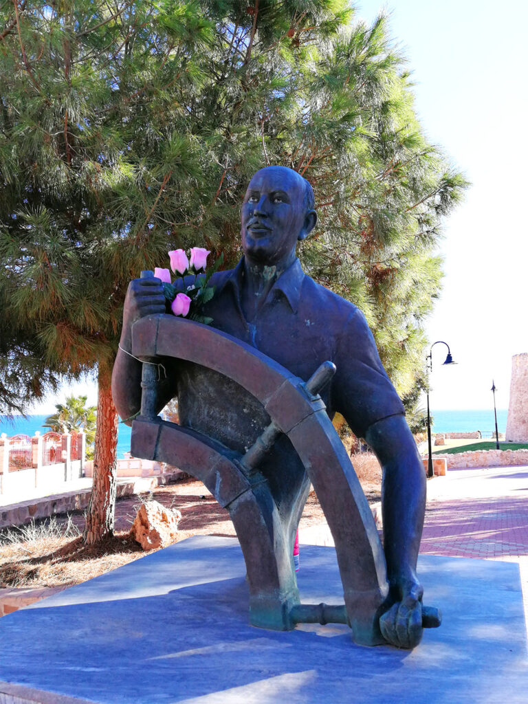 Staty av man som håller i ett stort seglarroder.