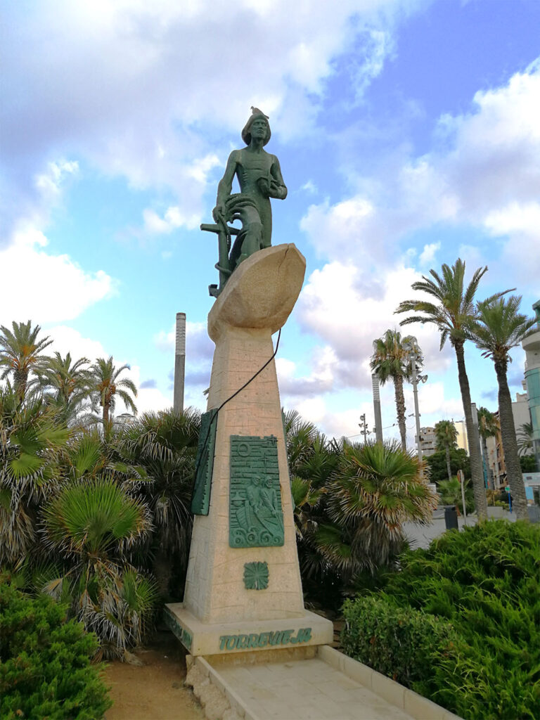 Pelare med en staty högst upp med en sjöman som håller ett ankare.