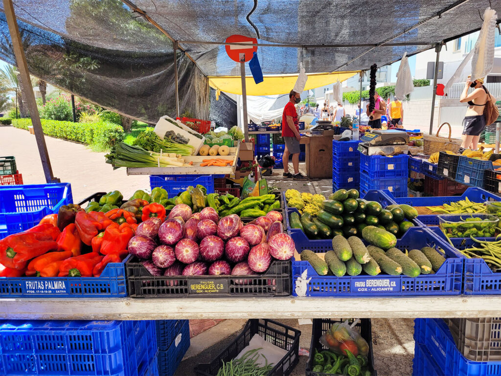 Marknad som säljer paprikor, auberginer och gurkor.