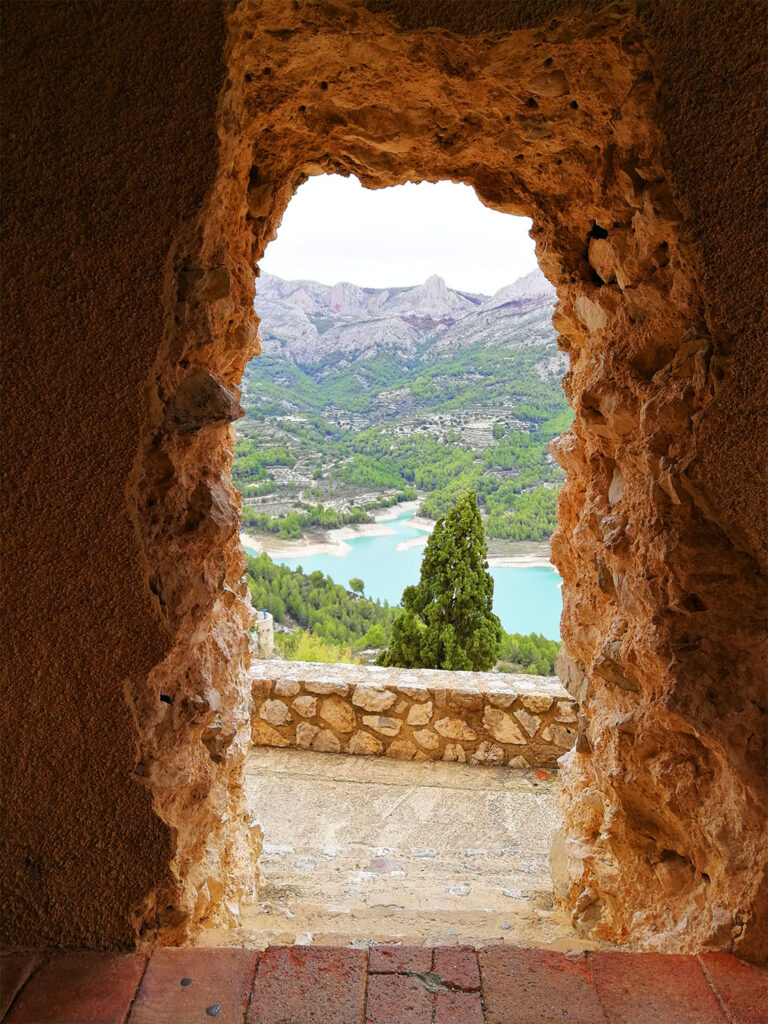 En stenig portal med utsikt över sjö och berg.