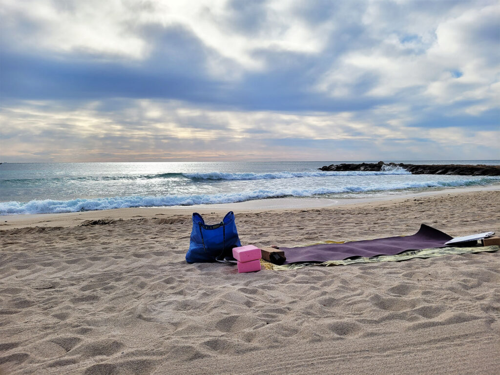 Yogamatta på sandstrand vid havet.